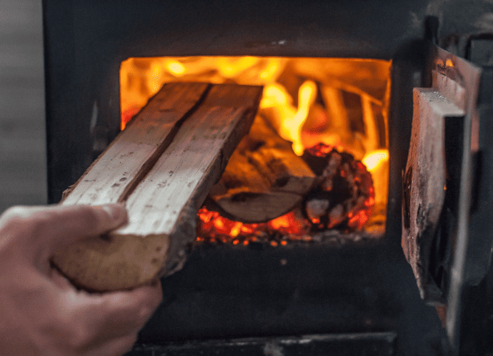 poêles à bois, personne qui alimente son poêle en bois buche